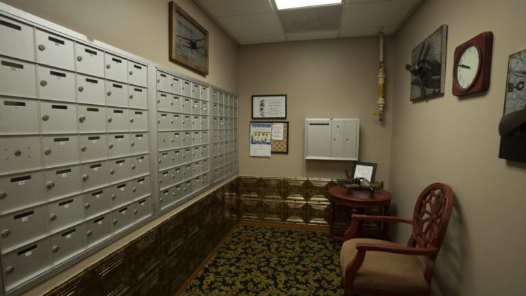 A quiet mailroom with multiple mailboxes and cozy seating.