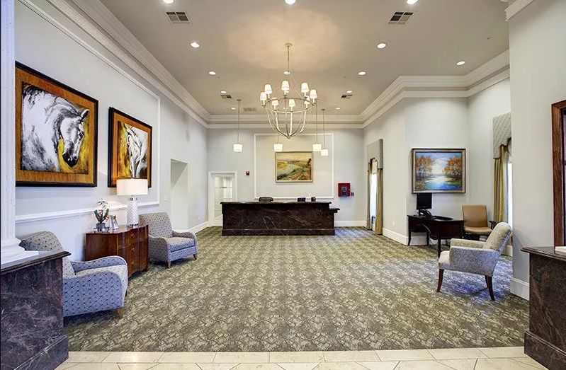 A spacious lobby with a central reception desk, elegant chandelier, and comfortable seating arrangement.