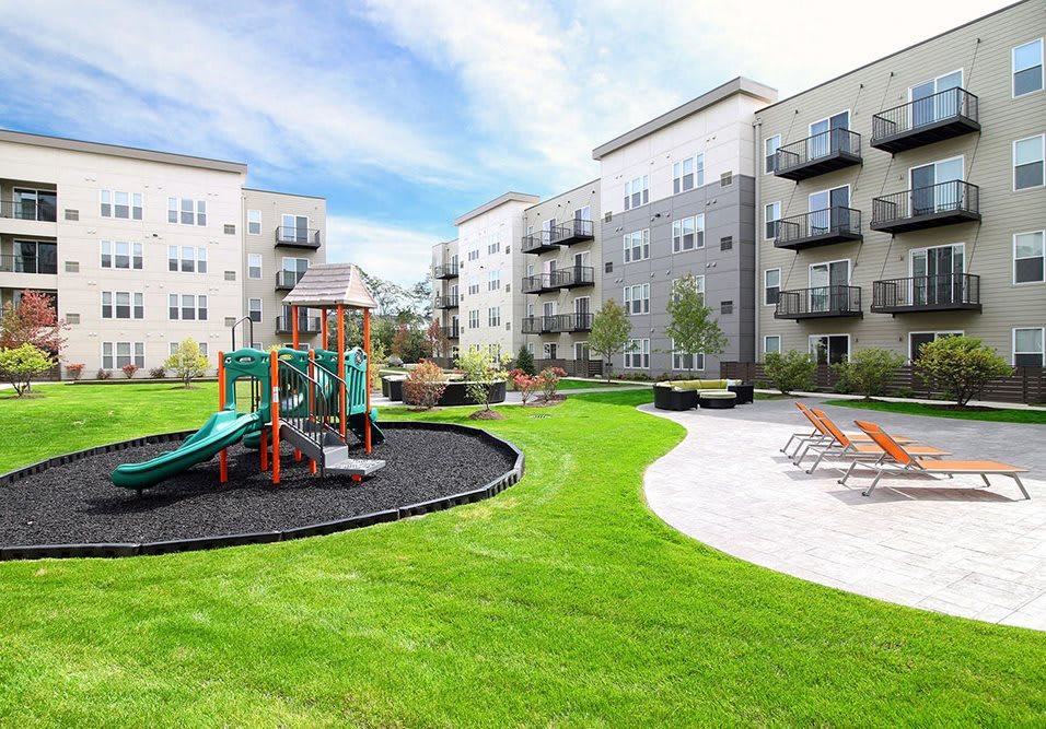 Modern apartment complex with a playground and green landscaped area.