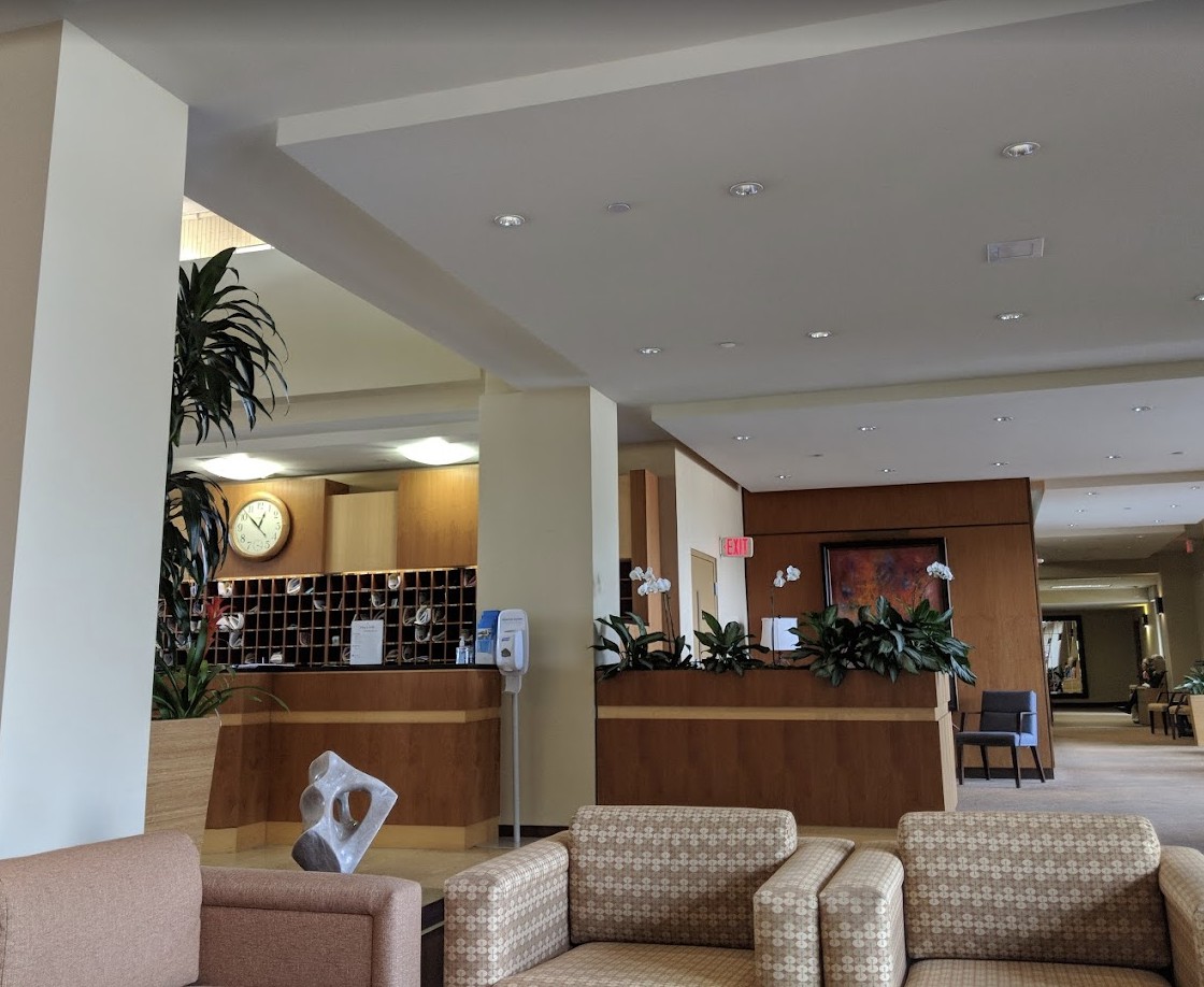A hotel lobby with a reception desk, seating area, and decorative plants.