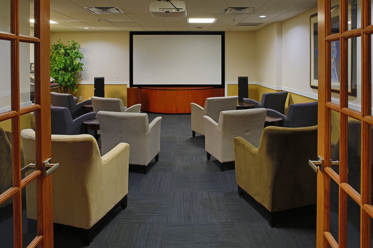 A cozy home theater setup with comfortable armchairs facing a large projector screen.