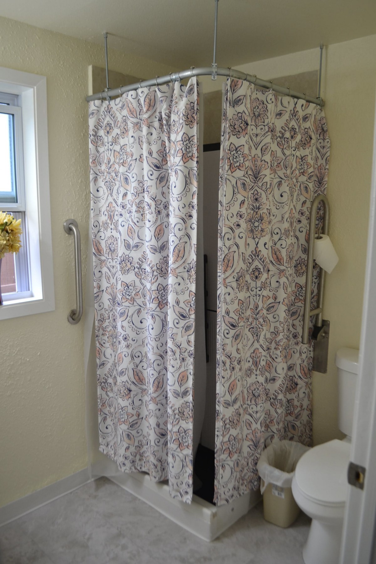 A bathroom with a patterned shower curtain and a small window.