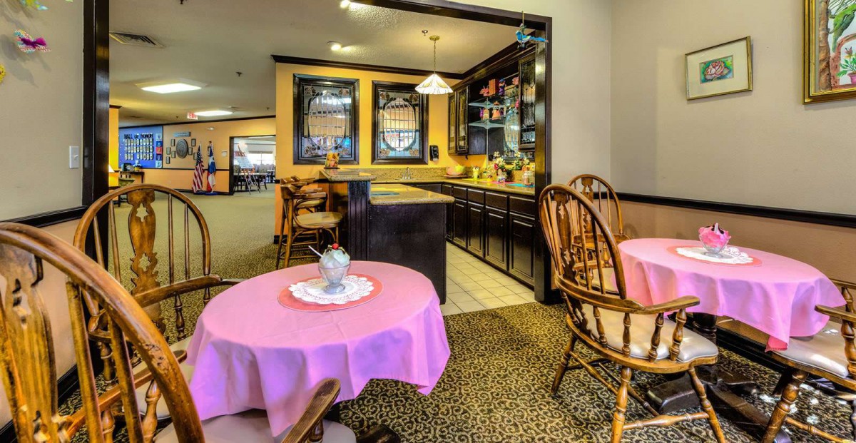 A cozy cafe interior with wooden chairs and tables covered with pink tablecloths.