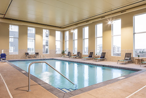 A serene indoor swimming pool, complete with lounge chairs and large windows allowing natural light to fill the space.