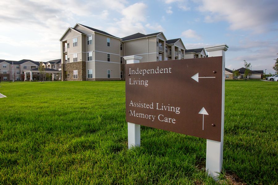 A directional sign in front of a retirement community complex indicating directions to independent living, assisted living, and mature care facilities.