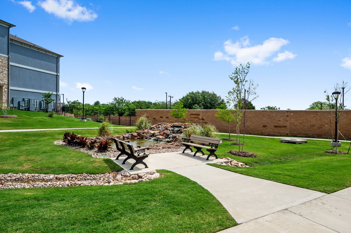 A serene park with benches and a pathway surrounded by lush greenery.