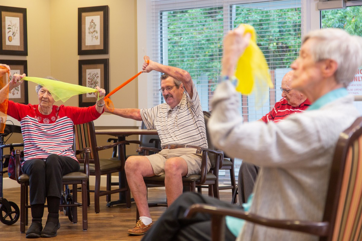 A group of seniors engaging in a fitness exercise using resistance bands indoors.