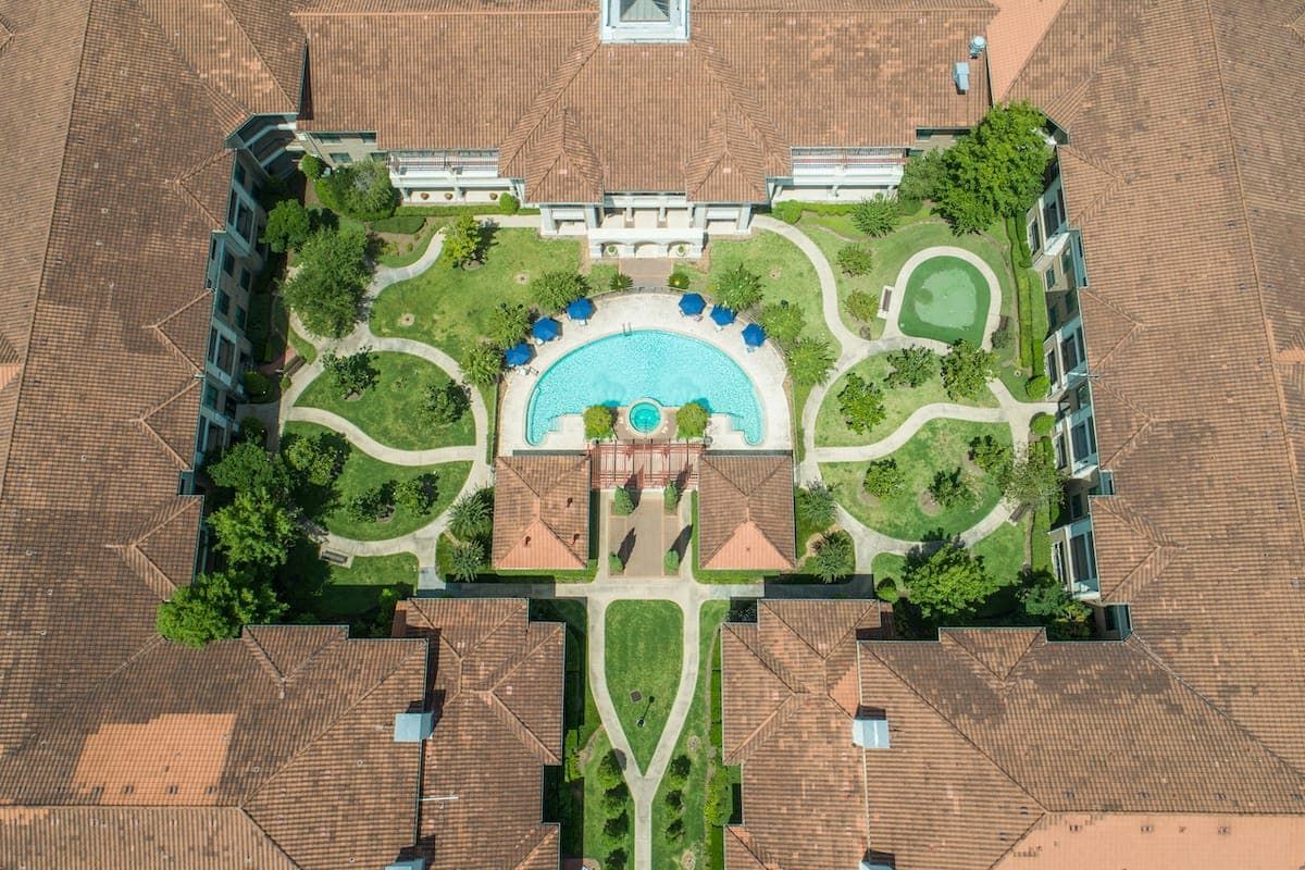 Aerial view of a landscaped courtyard with a swimming pool surrounded by greenery and architectural structures.