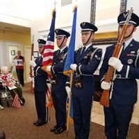 A military honor guard stands in formation holding flags during a ceremony.
