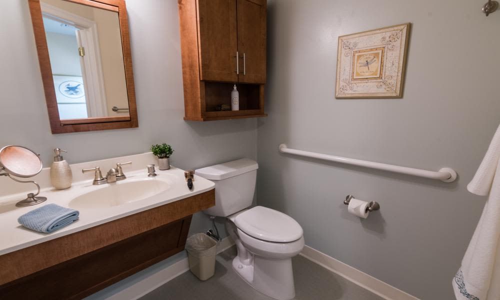 A small modern bathroom with a toilet, sink, and wall-mounted cabinet.