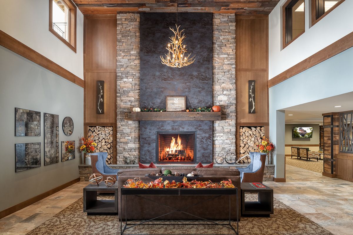 A cozy living room with a rustic stone fireplace and wooden decor.