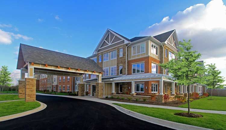 A modern residential building with a multi-story design and brick facade under a clear blue sky.