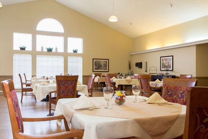 A spacious dining room with elegantly set tables and large windows letting in natural light.