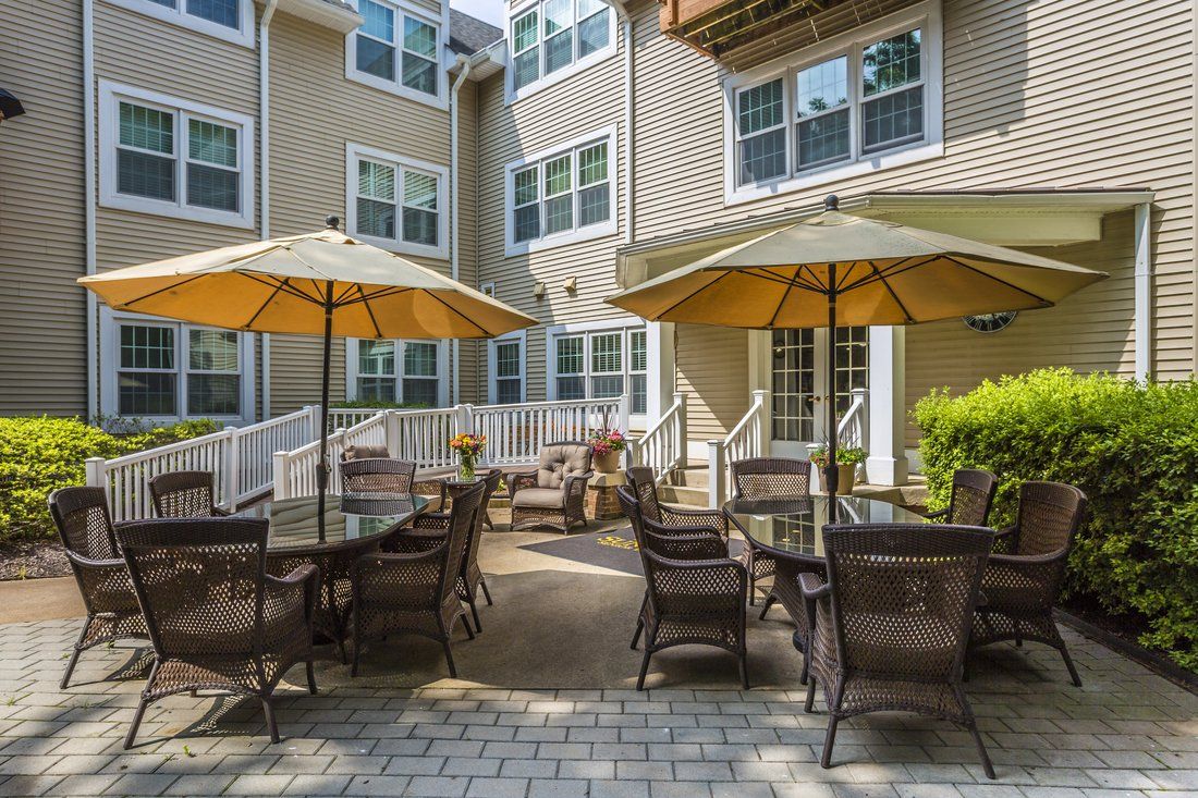 A cozy outdoor patio with tables, chairs, and umbrellas in a residential setting.