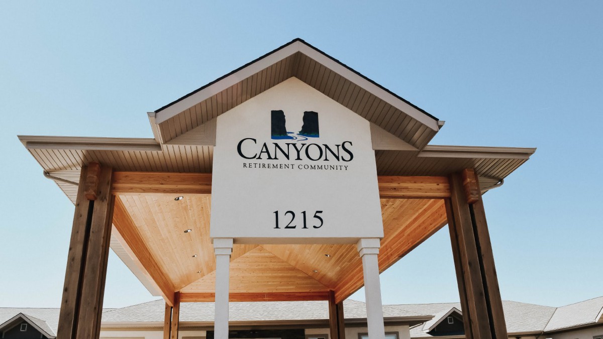 The entrance sign of Canyons Retirement Community displaying the address 1215 under a clear blue sky.