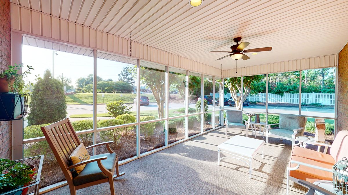 Bright and airy screened porch with comfortable seating and a ceiling fan.