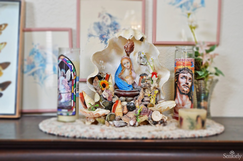 A small religious altar adorned with candles and figurines, surrounded by seashells.
