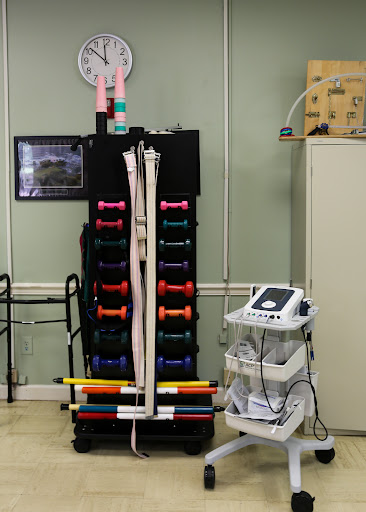 A well-equipped rehabilitation room featuring a set of colorful dumbbells and medical equipment.