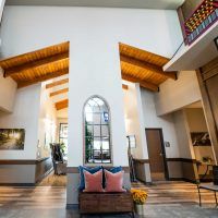 A modern lobby with high ceilings, featuring wooden beams and an arched window.