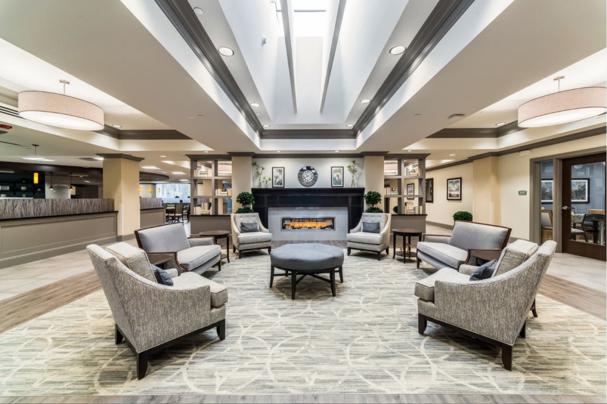 A modern lobby featuring comfortable seating around a central fireplace.