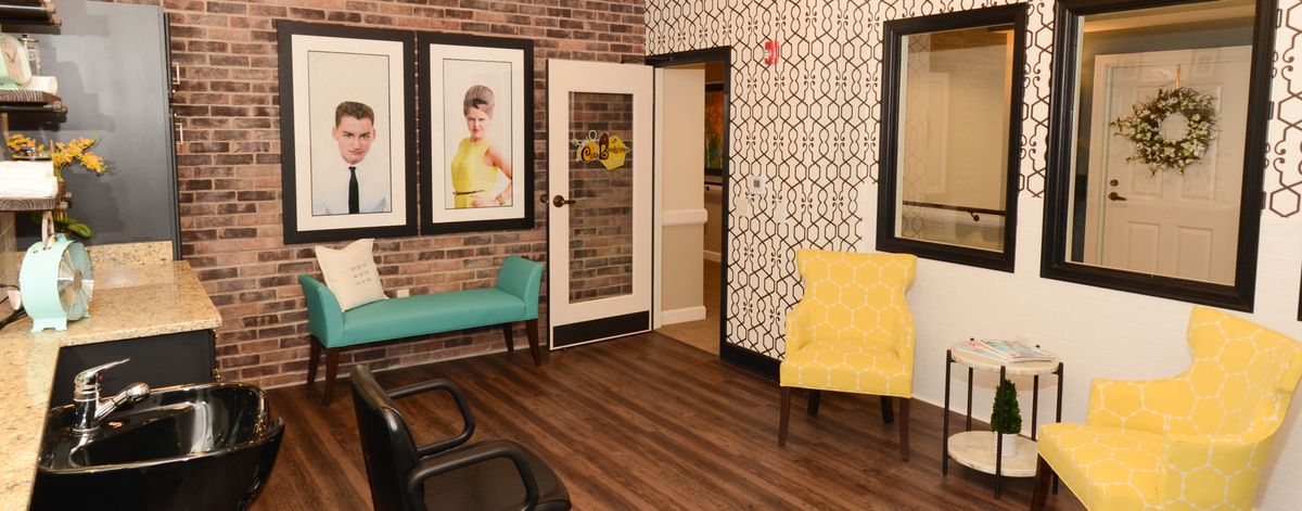 A modern waiting room with stylish seating, brick walls, and framed artwork.