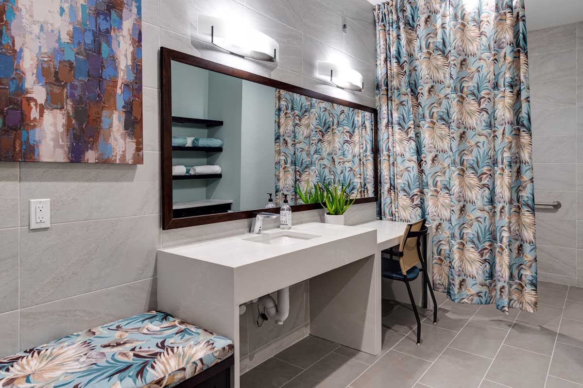 A modern bathroom with a large mirror, stylish lighting, and floral curtains.
