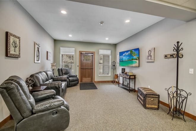 A cozy living room with leather seating, a large television, and tasteful decor.