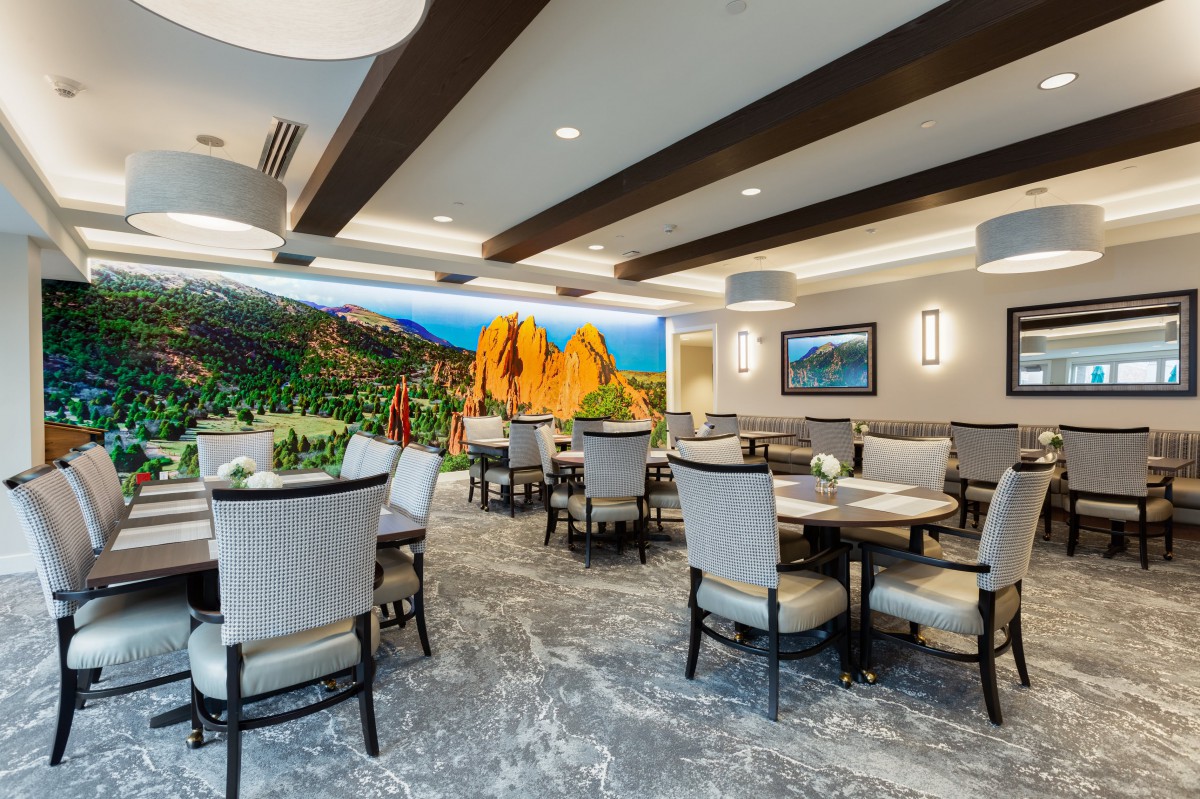 A modern dining area with elegant seating and a colorful mural on the wall.
