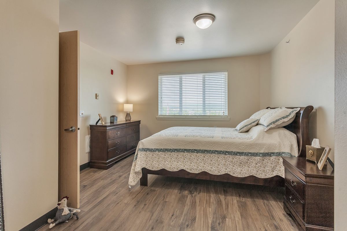 A cozy bedroom with a neatly made bed and wooden flooring.
