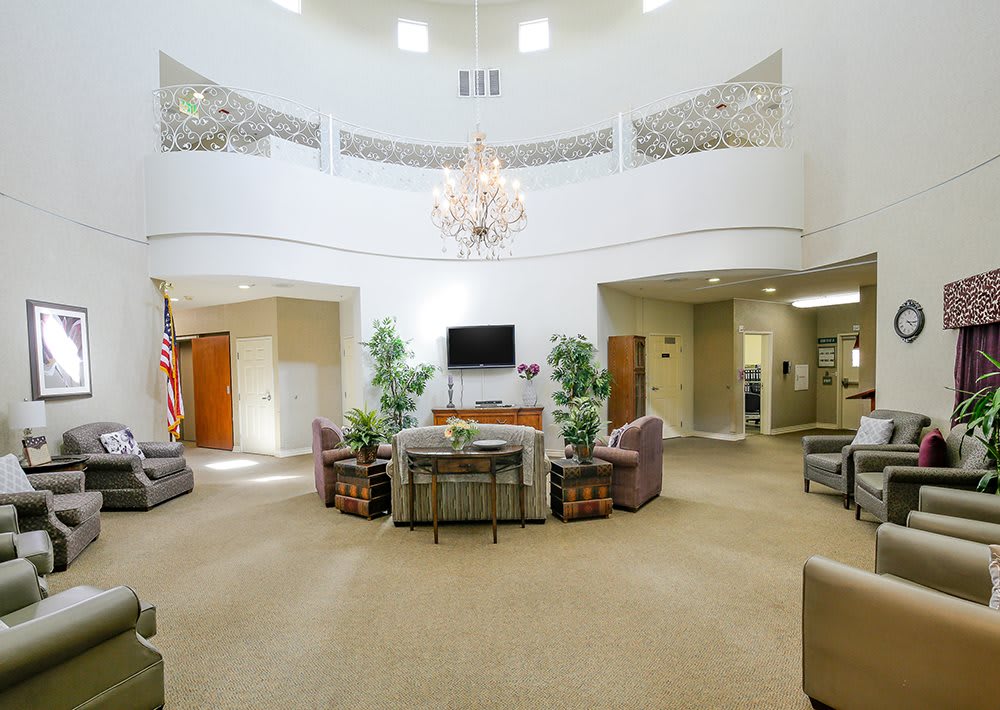 A spacious lobby with a central seating area, chandelier, and decorative plants.