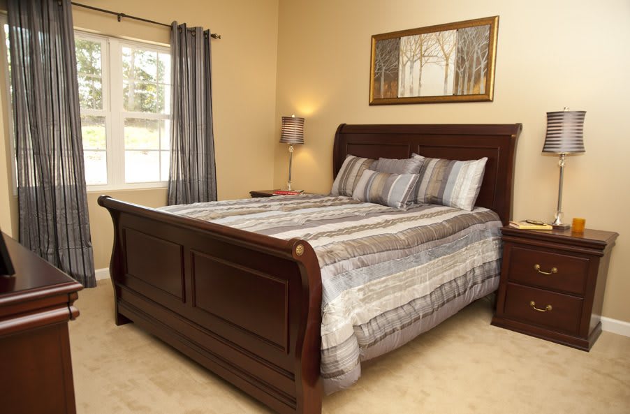 A cozy bedroom with a wooden sleigh bed, striped bedding, and wall art above.
