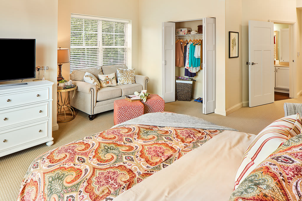 A cozy bedroom interior with a bed, sofa, and closet space.