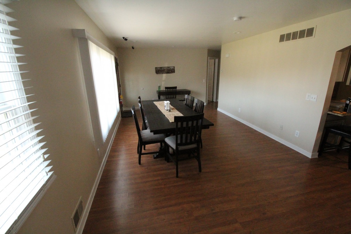 A minimalist dining room with a large table and chairs on a hardwood floor.