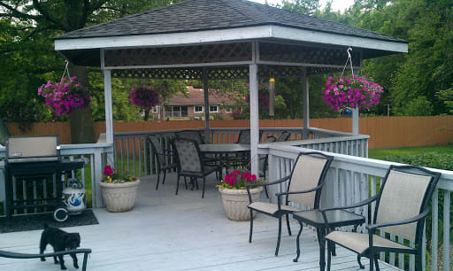 An inviting gazebo with outdoor seating and vibrant flowers in pots and hanging baskets.