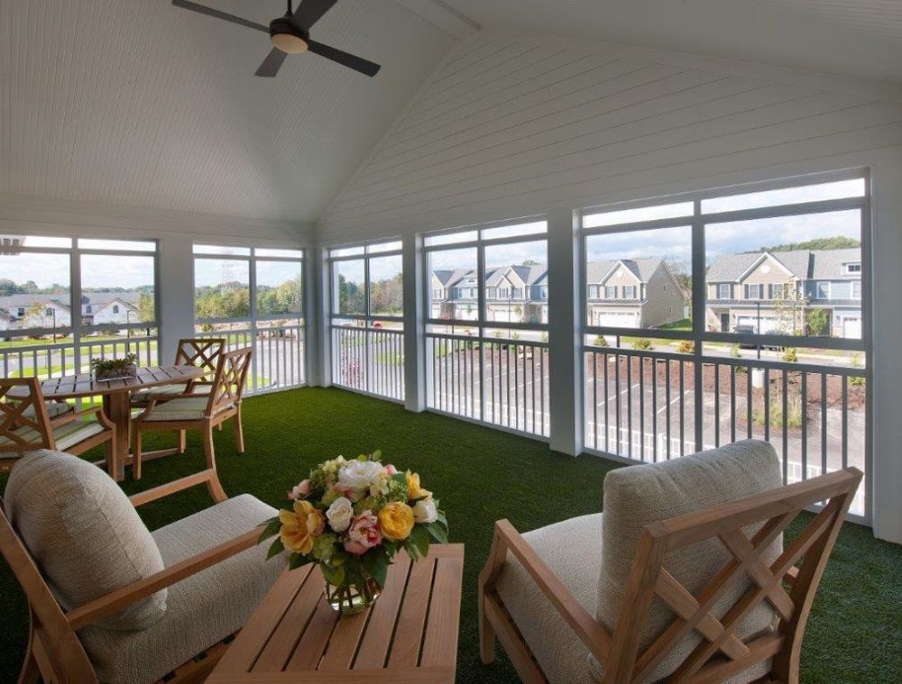 A cozy sunroom with wooden furniture and a flower centerpiece, offering a bright view of the outdoors.