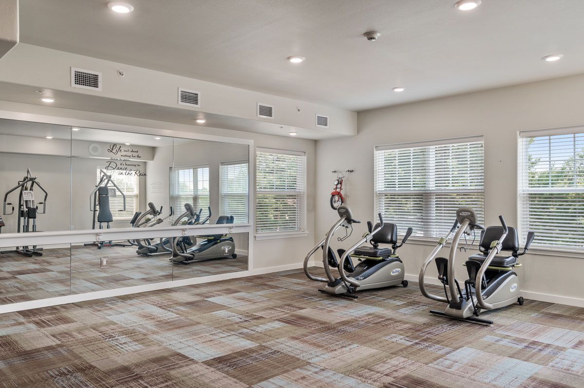 A modern gym with exercise equipment including stationary bikes and large mirrors.