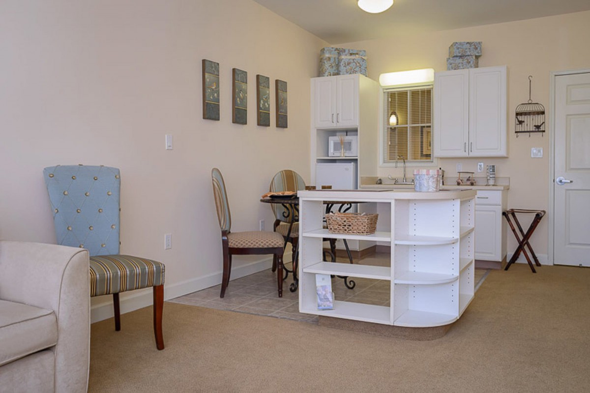 A cozy kitchen and dining area featuring a small table with chairs and open shelving.