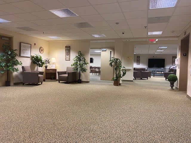 A spacious office lobby with seating arrangements and plants, leading to a conference room.