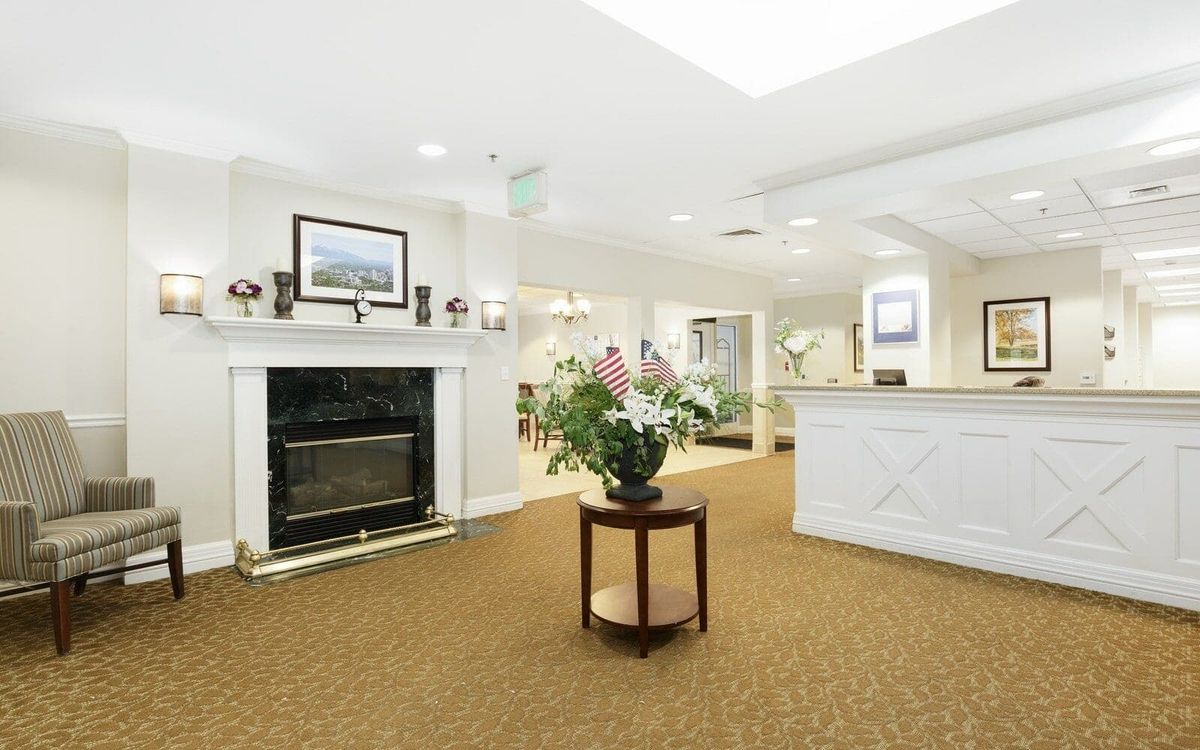 A well-lit lobby area featuring a reception desk, fireplace, and decorative plants.