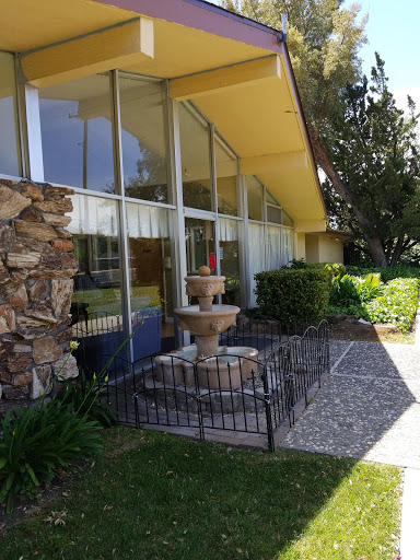 A modern architectural structure featuring a decorative fountain and landscaped gardens.