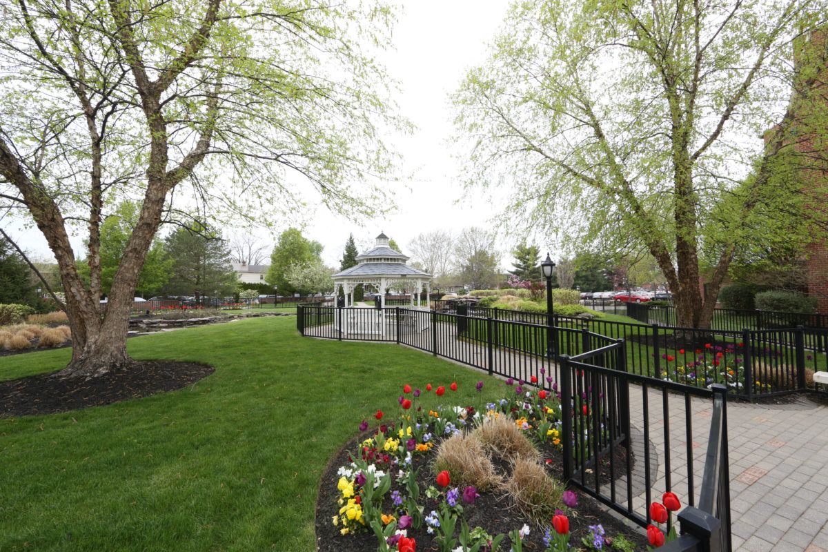 A serene park landscape featuring a gazebo surrounded by lush greenery and colorful flower beds.