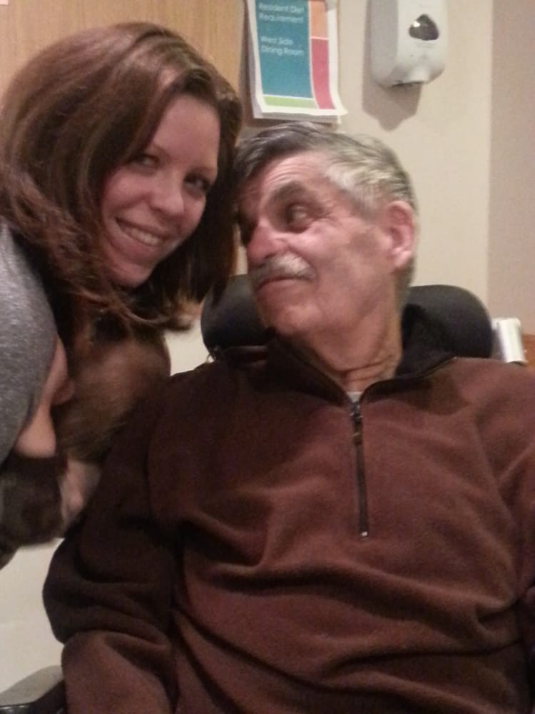 A woman smiling at a seated man indoors.