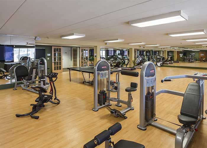 A spacious gym with various exercise equipment and mirrors lining the walls.