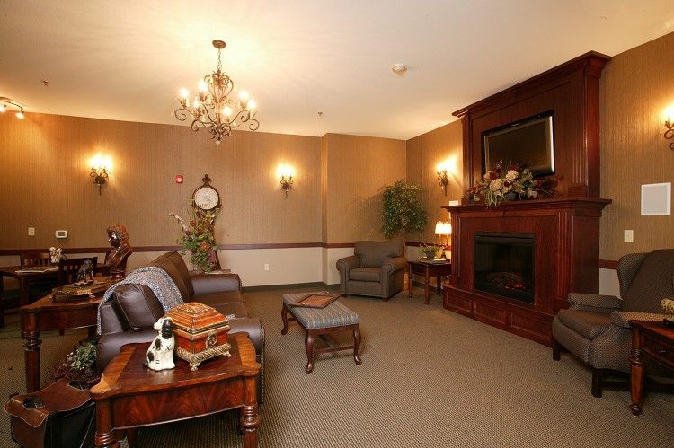 A cozy living room with leather couches, a fireplace, and a chandelier.