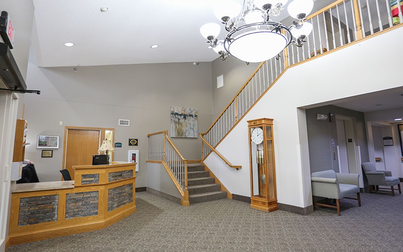 A spacious reception area featuring a staircase, clock, and chandelier.