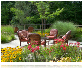 A serene garden with outdoor seating surrounded by vibrant flowers and lush greenery.