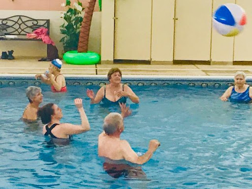 Adults enjoying a lively game in the swimming pool.