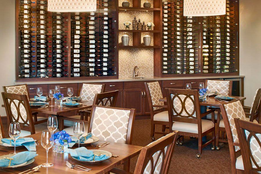 A cozy restaurant dining area with elegant table settings and a wall of wine racks.