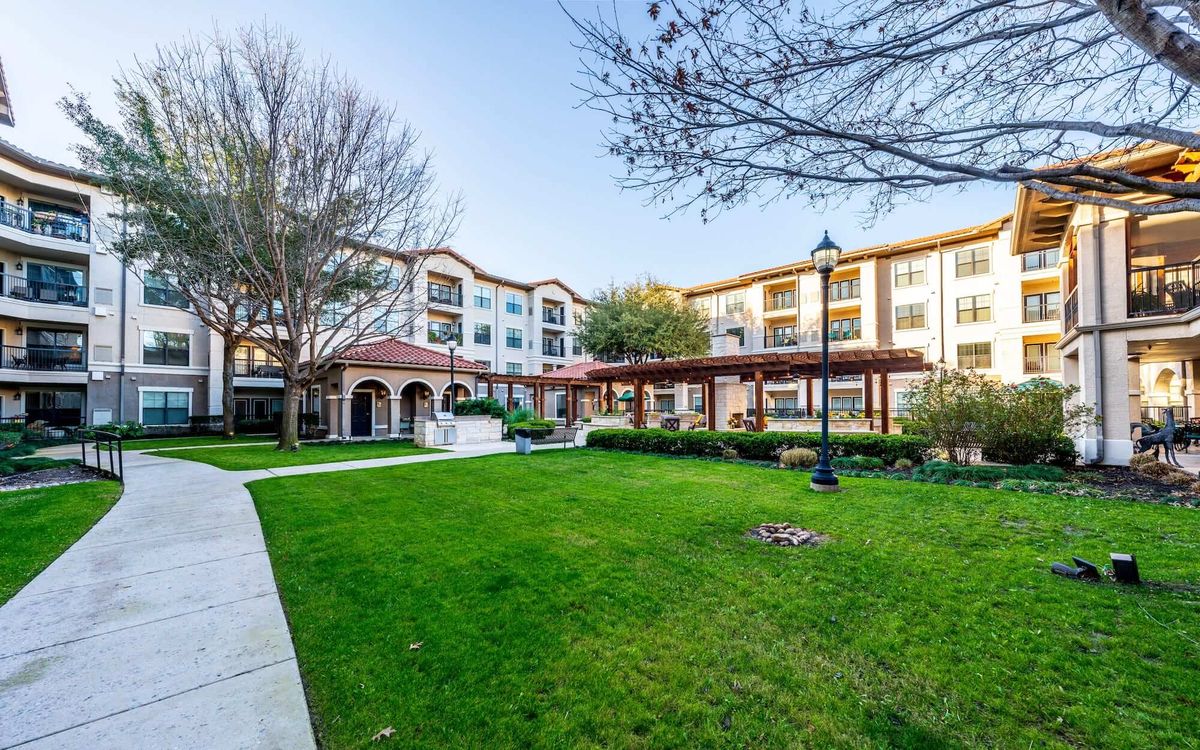 A residential building with manicured lawns and trees surrounding it, showcasing a serene and well-maintained landscape.