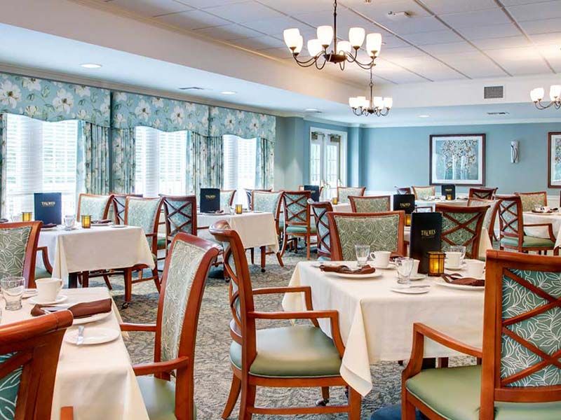 An elegant restaurant dining room with neatly arranged tables and chairs, featuring a chandelier.